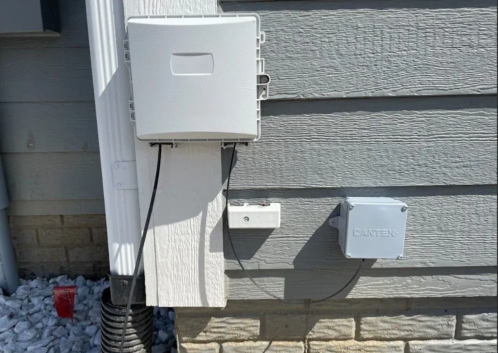 Exterior view of a house with mounted white boxes for telecommunications or utility connections.