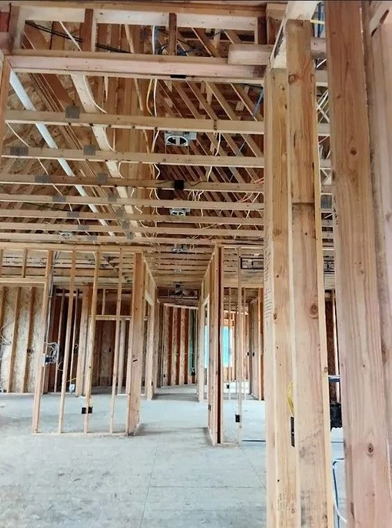 Interior framing of a building under construction, showing wooden studs, beams, and open spaces.