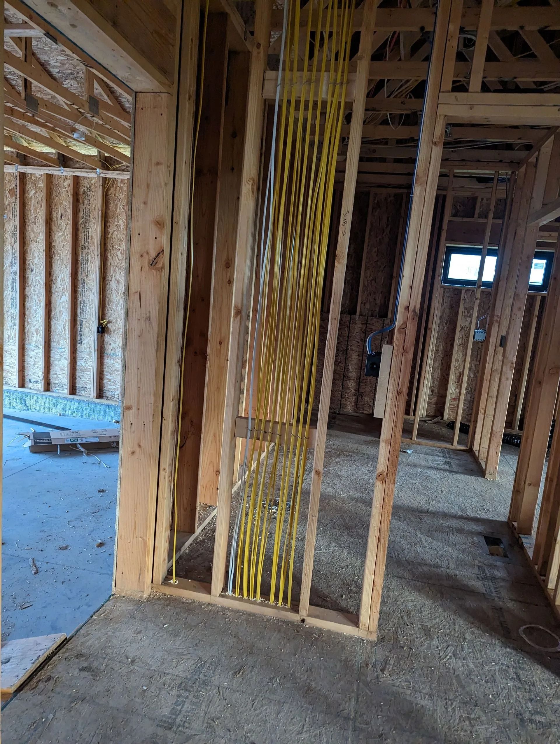 Interior framing of a building with bundles of yellow electrical wiring.