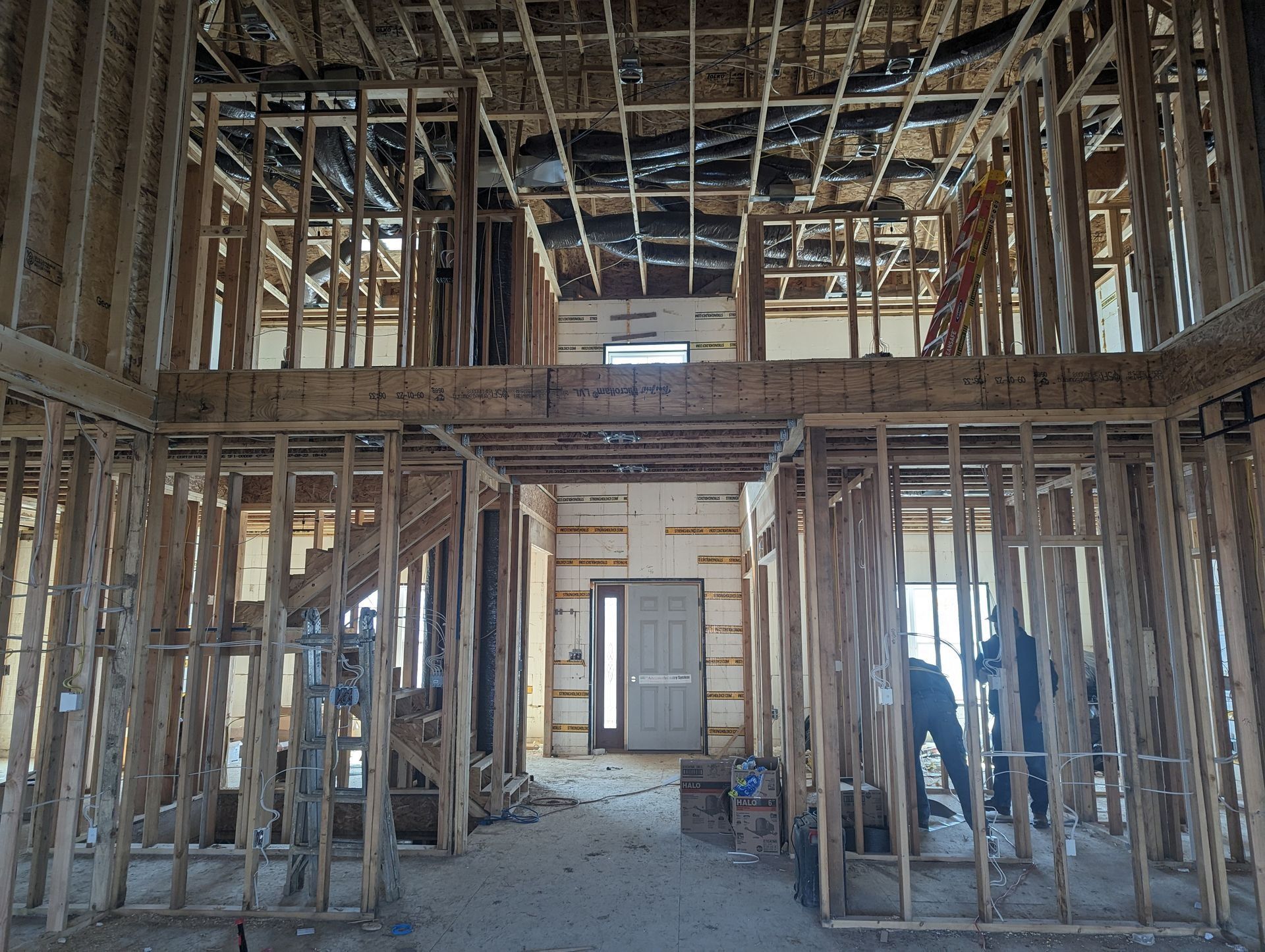 Interior view of a building under construction, showing exposed wooden framework and a doorway.