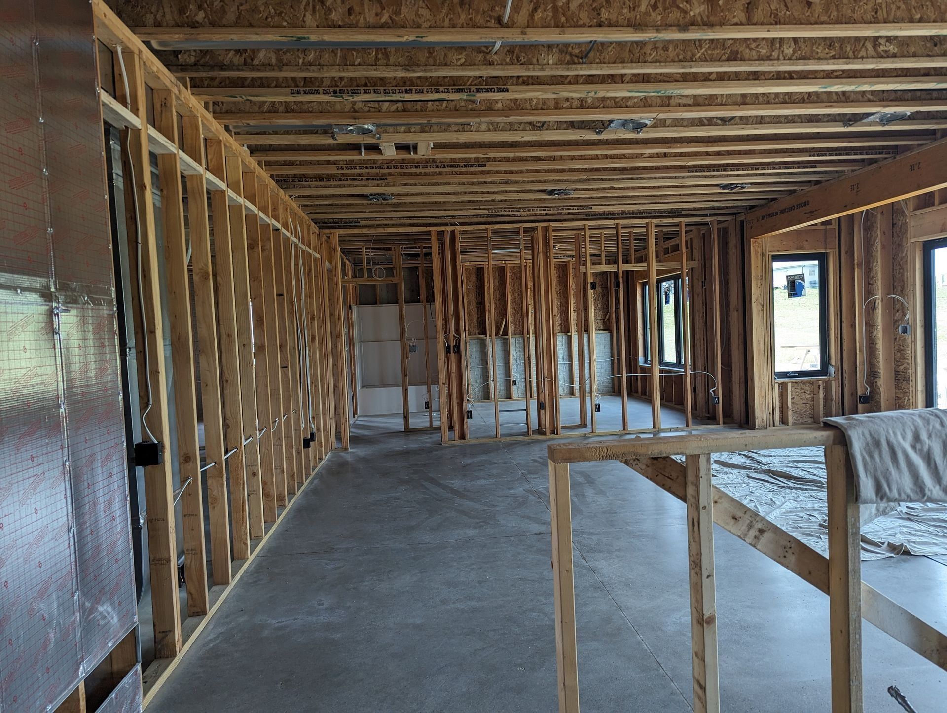 Interior of a building under construction, showing wooden framing and concrete floor.