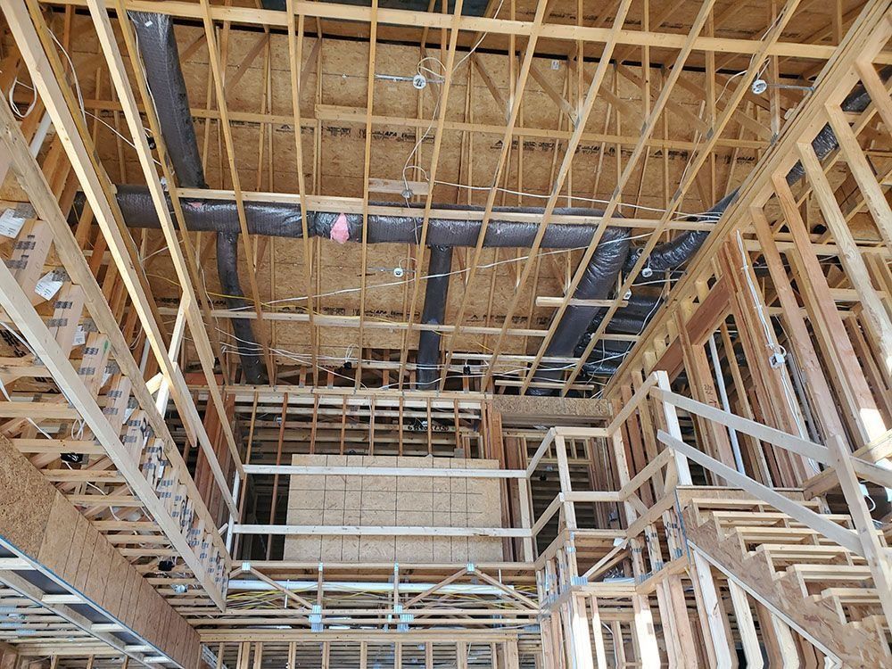 Wooden house frame, plumbing visible in the ceiling, stairs on the right, insulation present.