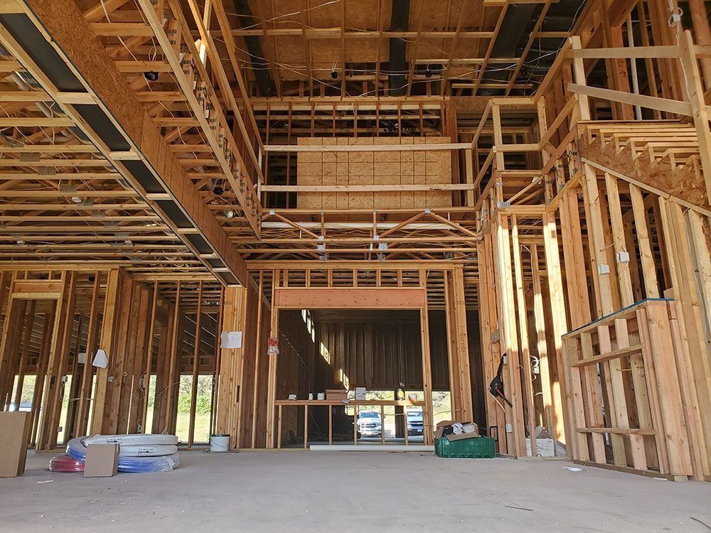 Interior view of a building under construction, framed with wooden beams and studs.