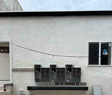 White wall with multiple electrical meter boxes and a window. A door is on the left.