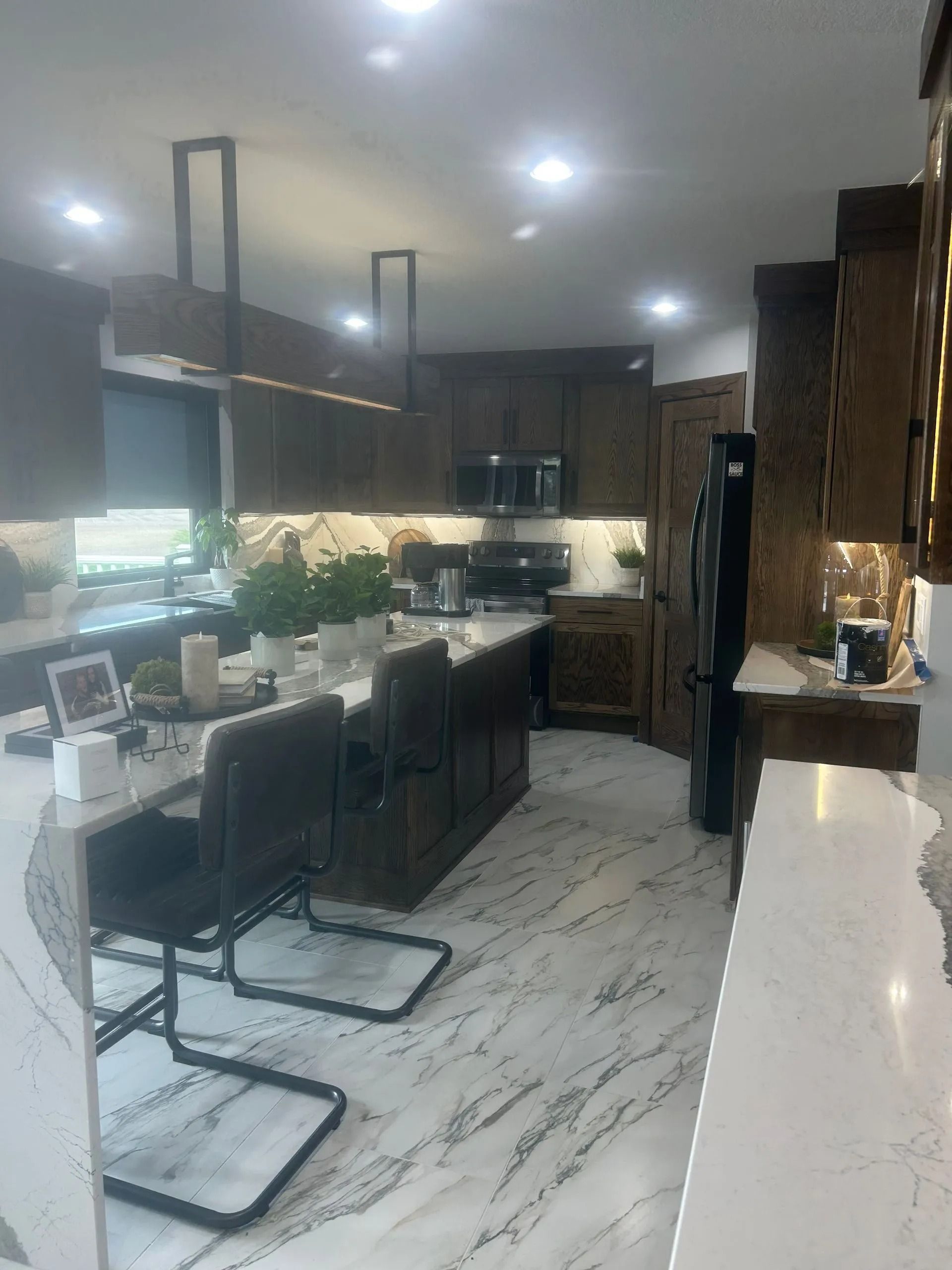 Modern kitchen with marble countertops, dark wood cabinets, and bar seating.