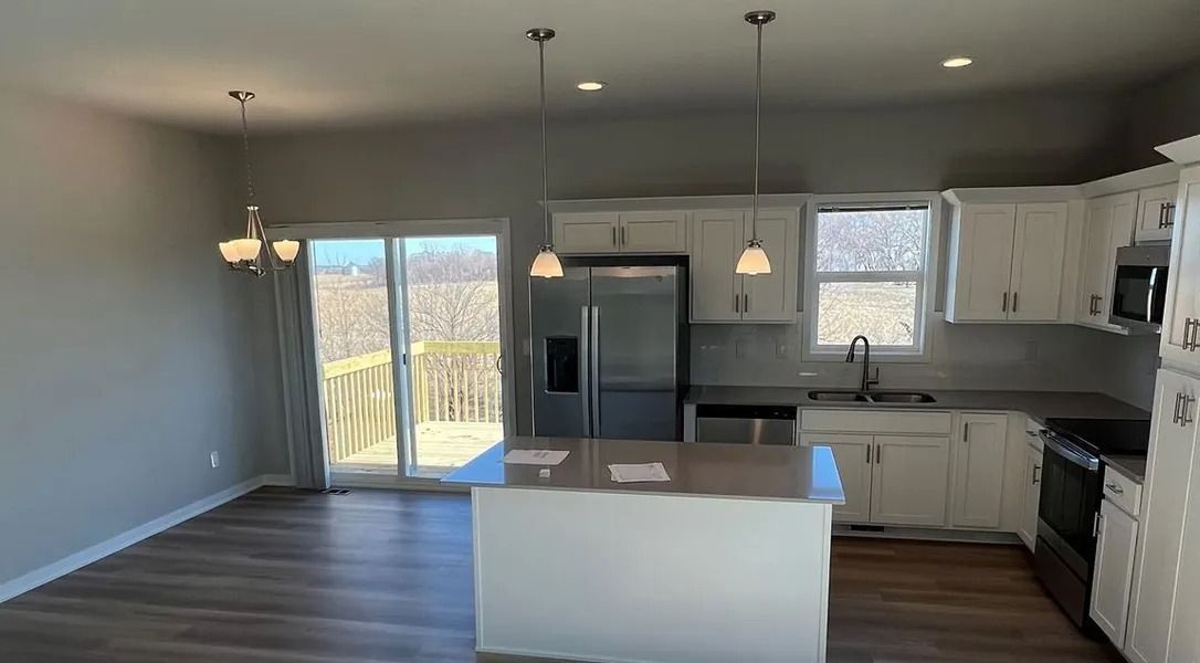 Kitchen and dining area with white cabinets, stainless steel appliances, and island with a deck outside a sliding glass door.