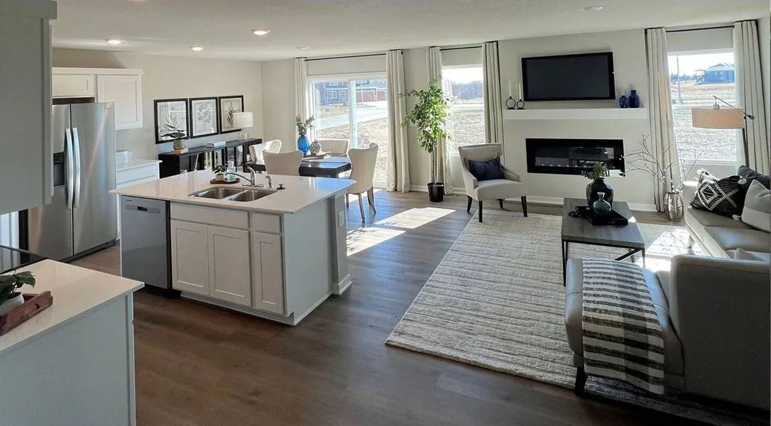 Open-concept living space with a kitchen island, dining area, and living room with a fireplace and television.