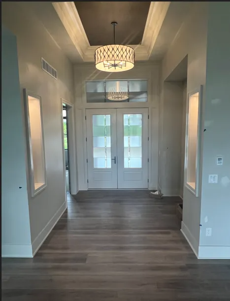 Hallway with wood floors and double doors; light fixtures and recessed lighting.