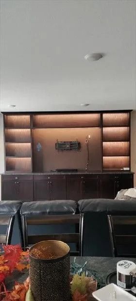 Built-in dark wood entertainment center with cabinet doors, shelves, and recessed lighting.