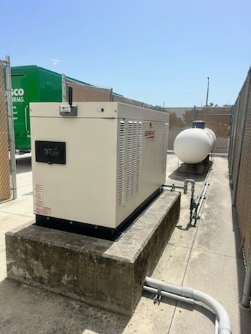 Rooftop HVAC unit beside a large white tank on a concrete platform under a clear sky
