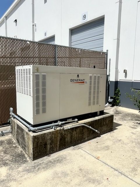 Outdoor generator unit beside a white industrial building and roll-up door