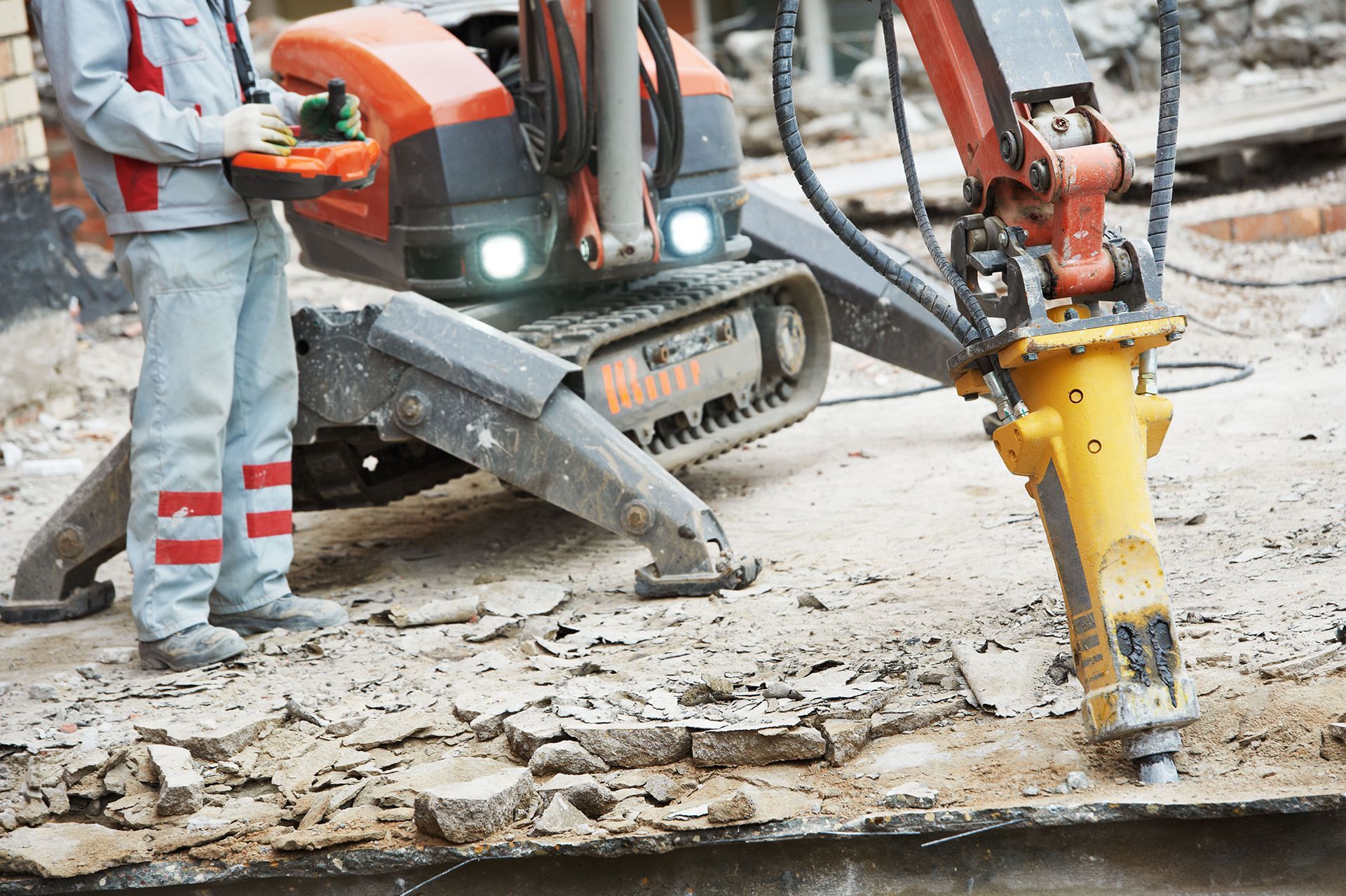 A man is standing next to a machine that is breaking concrete