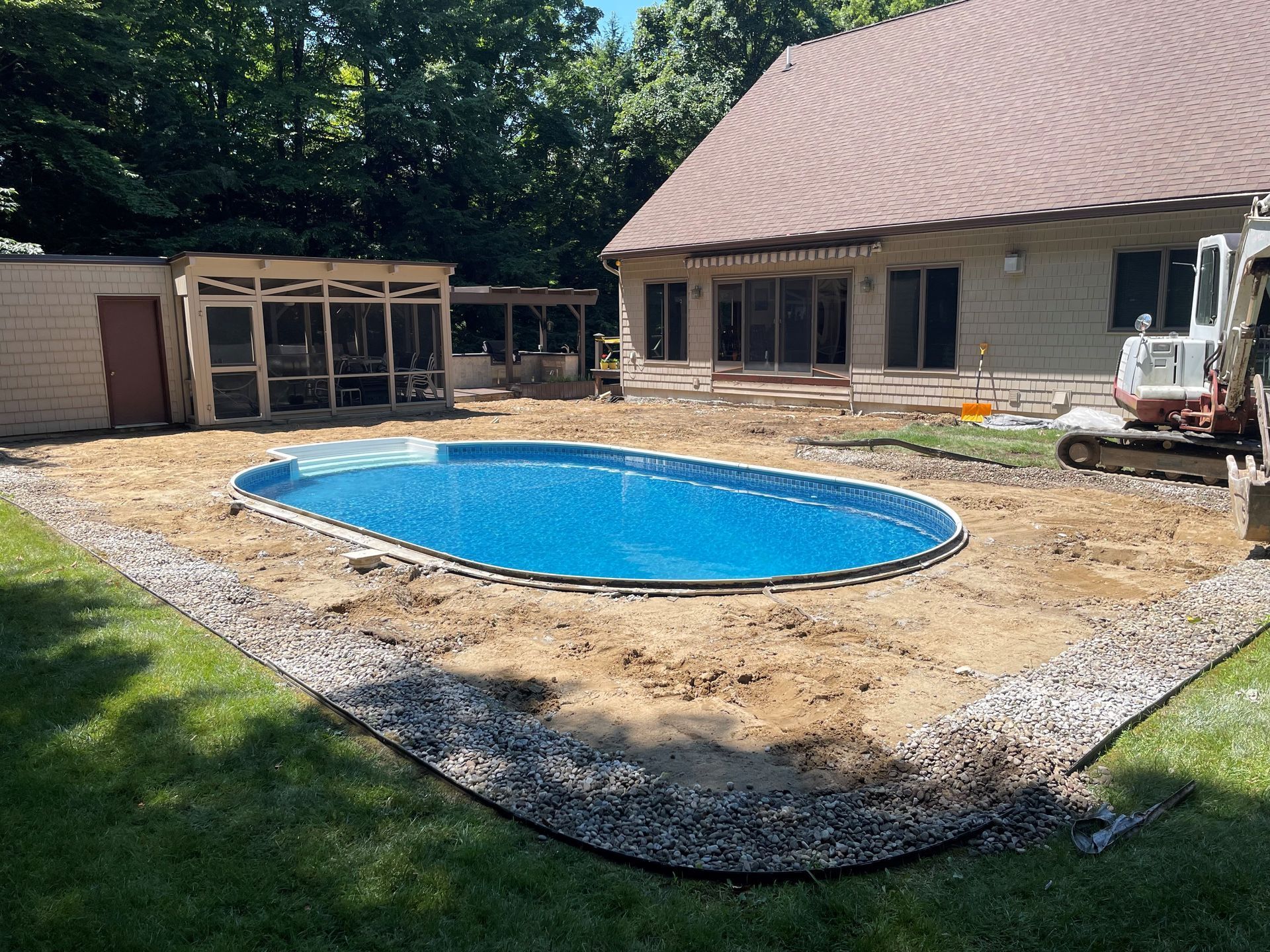 A swimming pool is being built in the backyard of a house