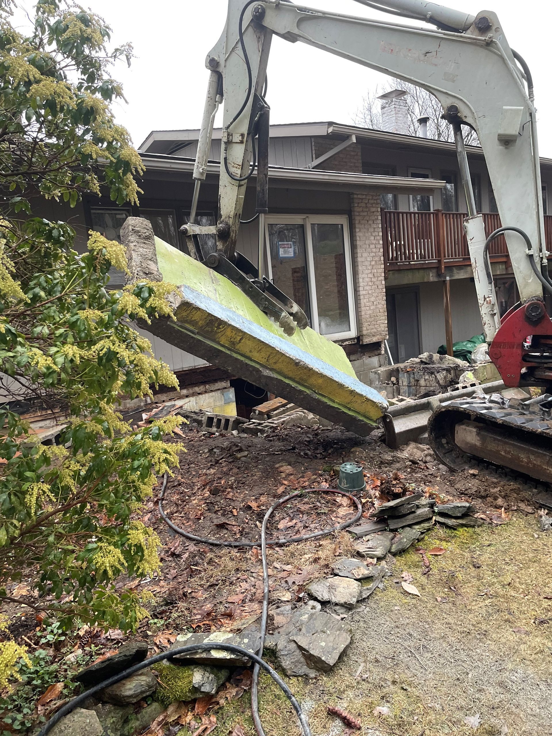 A house is being demolished by an excavator