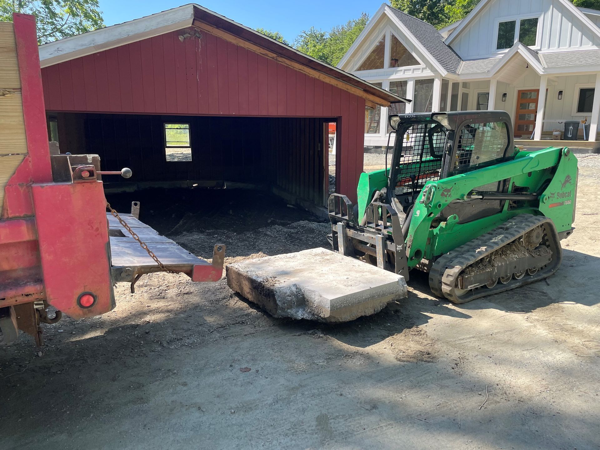 A green bulldozer is pulling a large rock out of a garage