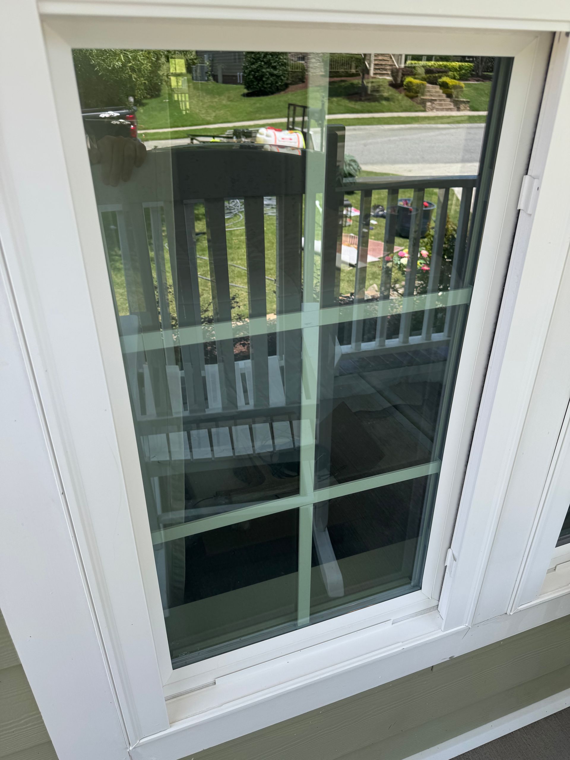 A white window with a reflection of a balcony in it.