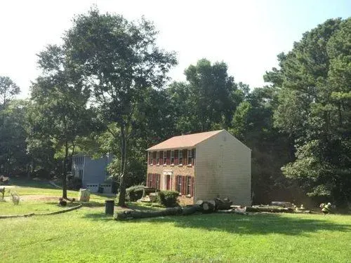Rural house under construction with trees and grass around it on a sunny day