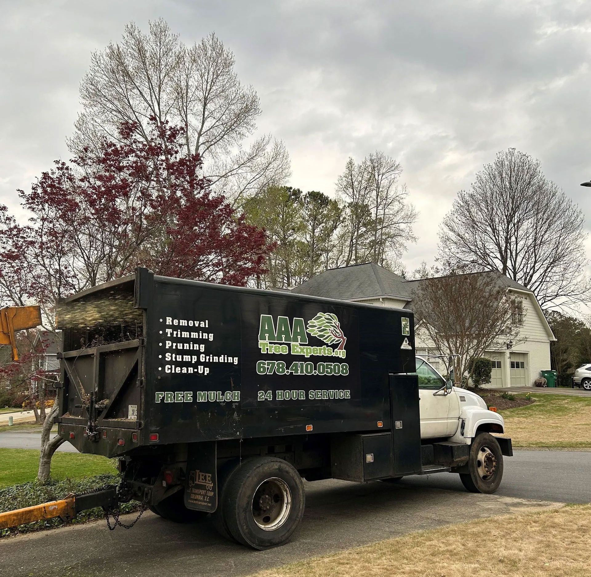 Black dump truck parked on a driveway in a suburban neighborhood on a cloudy day