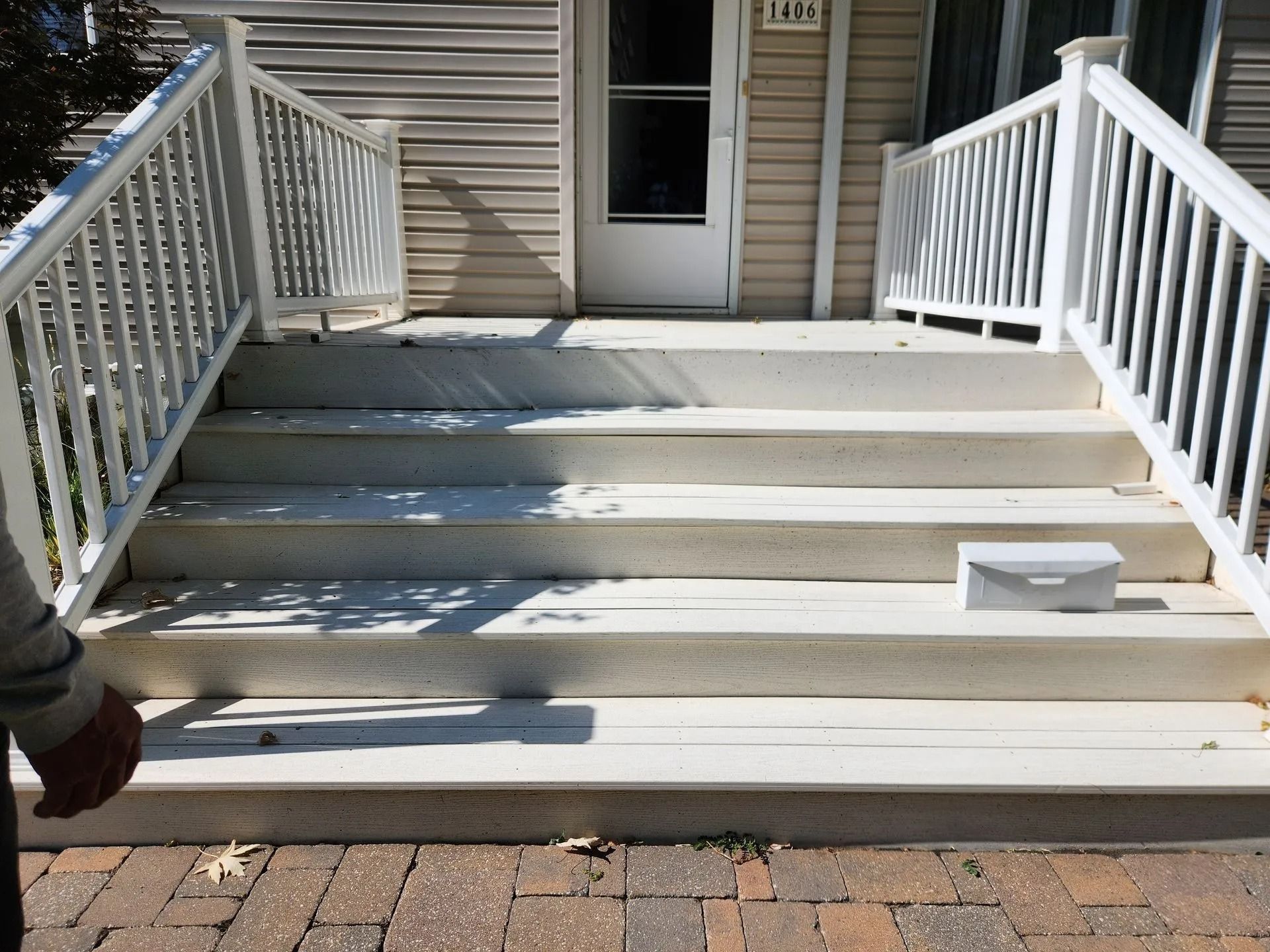 White concrete steps leading to a front door with white railings and a gray mailbox.