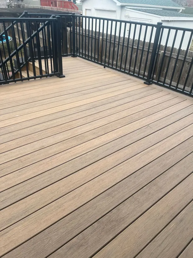 Wooden deck with black railing overlooking a yard.