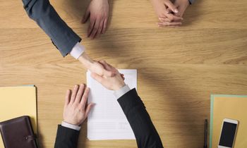 a group of people are shaking hands over a piece of paper