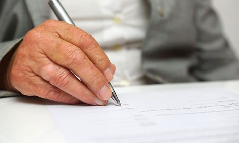 a man is writing on a piece of paper with a pen