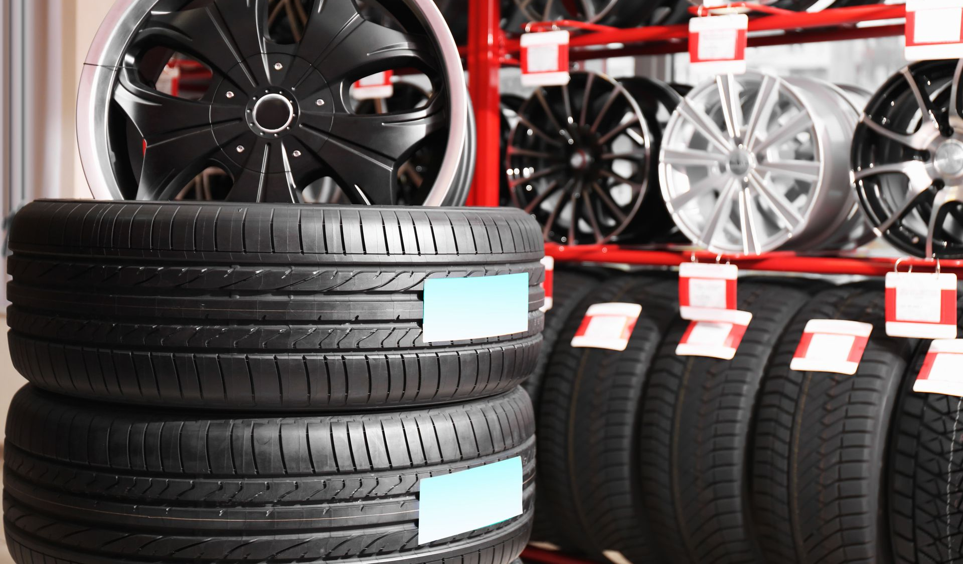 Stacks of black tires and car rims displayed in a tire shop warehouse.