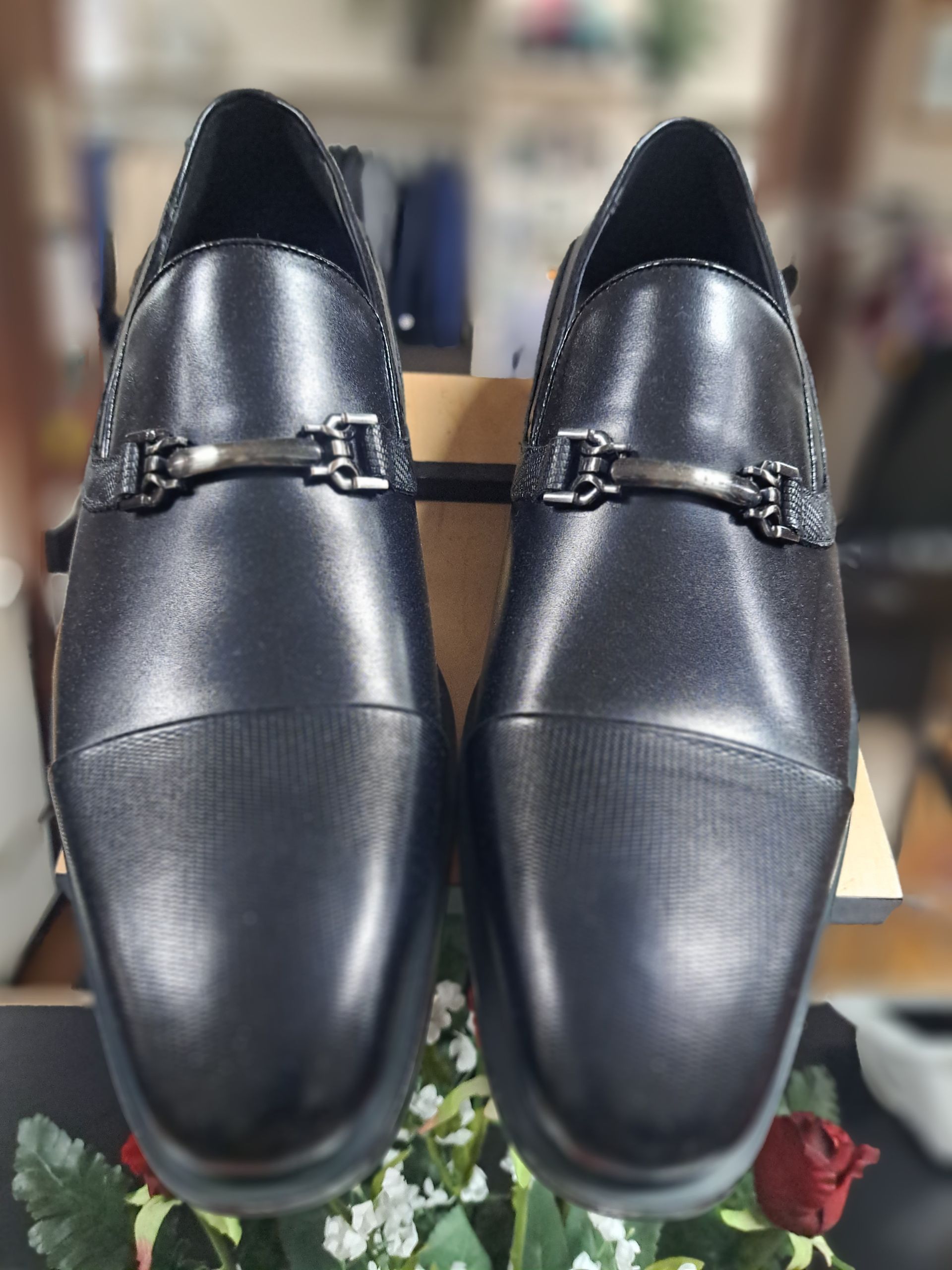 a pair of mens black dress shoes are sitting on top of a wooden shelf .