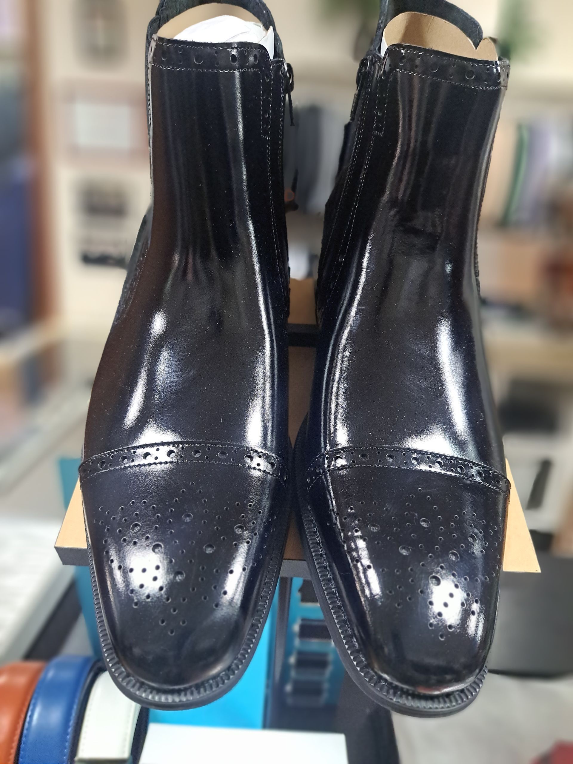 a pair of mens black formal boots sitting on top of a table