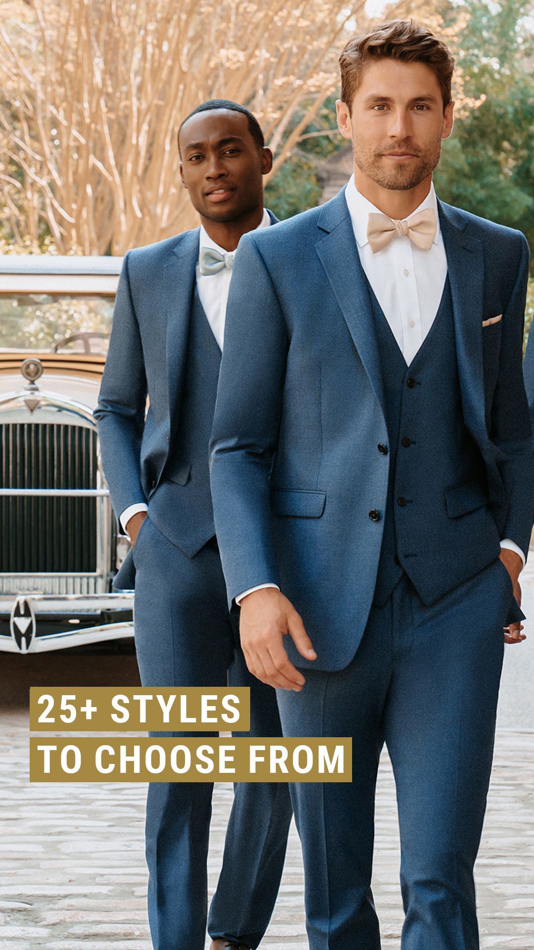 Two men in blue suits and bow ties in front of a vintage car