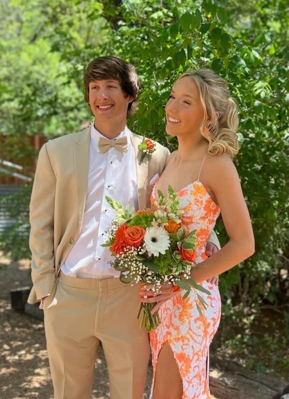 A man and a woman are posing for a picture while the woman is holding a bouquet.