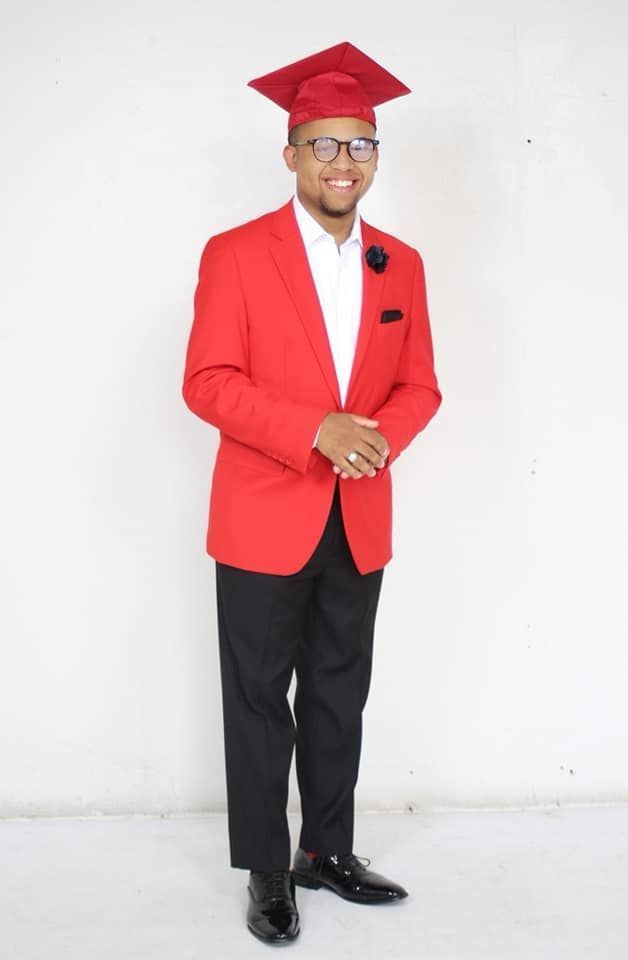 A man wearing a red graduation cap and suit.