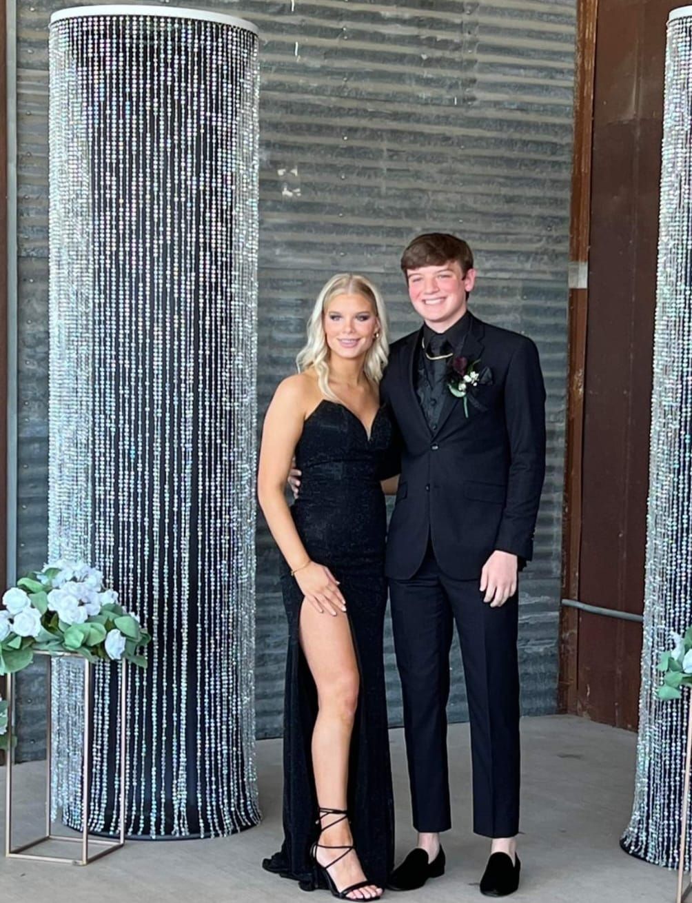 A woman in a black dress and a man in a suit are posing for a picture.