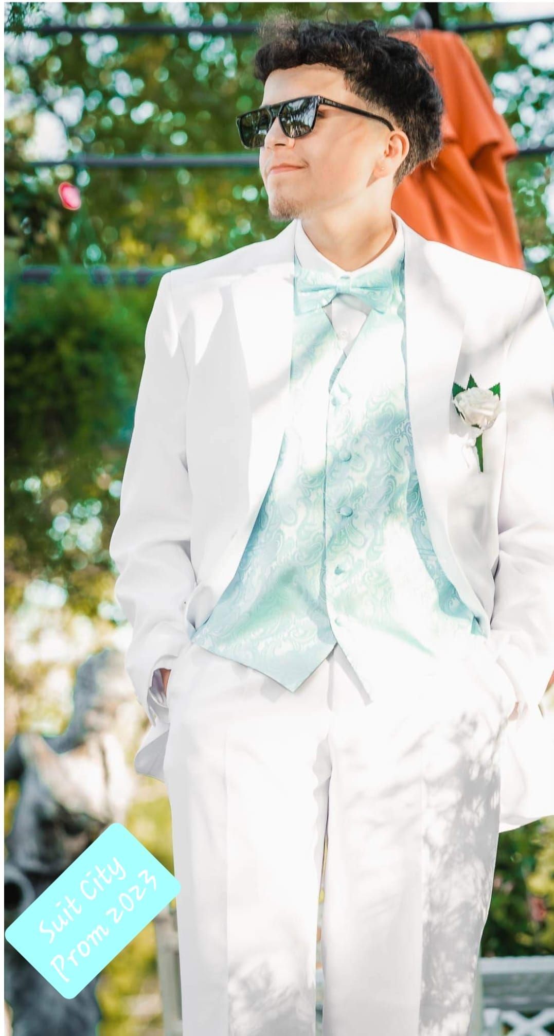 A man in a white suit and bow tie is standing with his hands in his pockets.