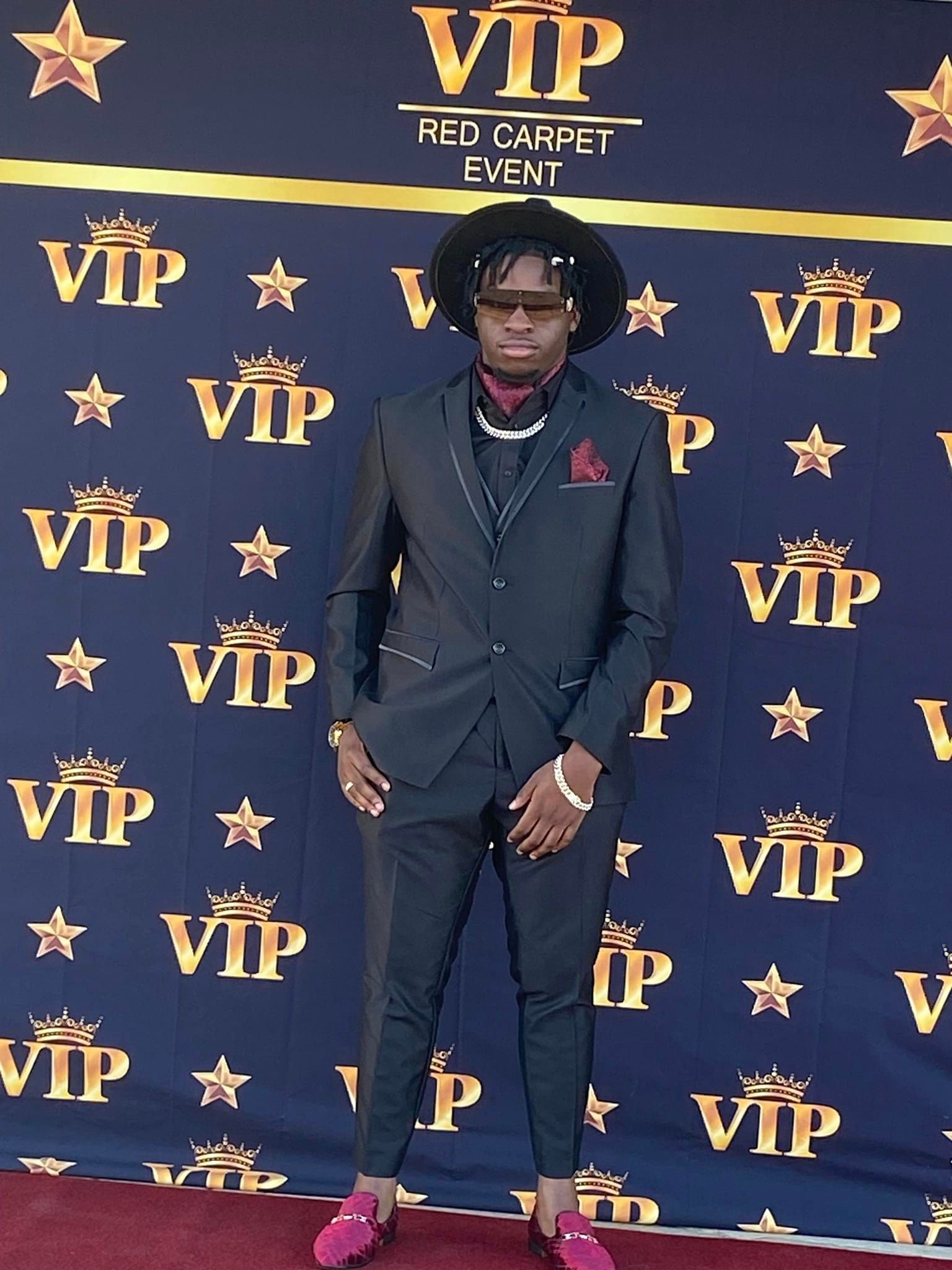 A man in a suit is standing in front of a VIP backdrop.
