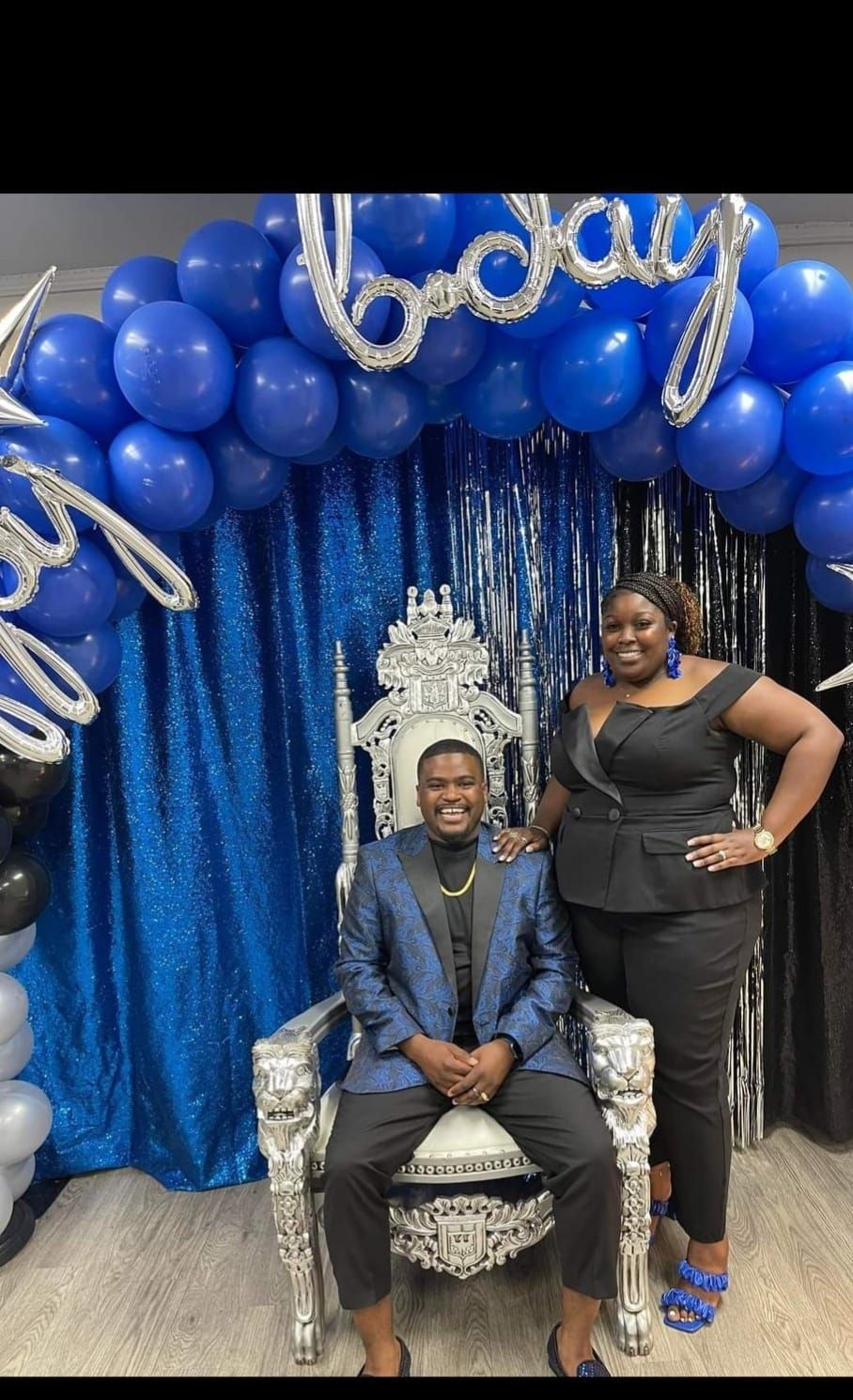 A man in a suit is sitting on a throne next to a woman.