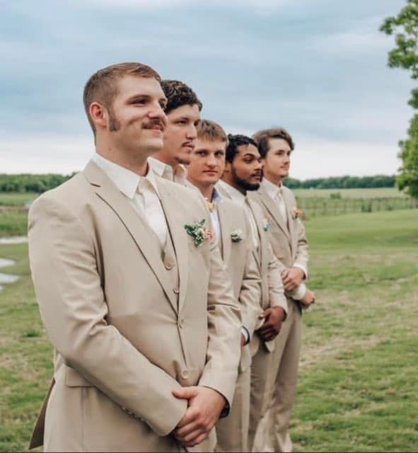 A group of men in suits are standing in a field.