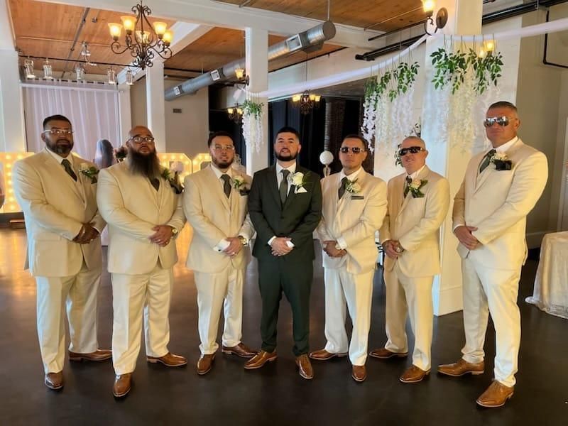 A groom and his groomsmen are posing for a picture at a wedding.
