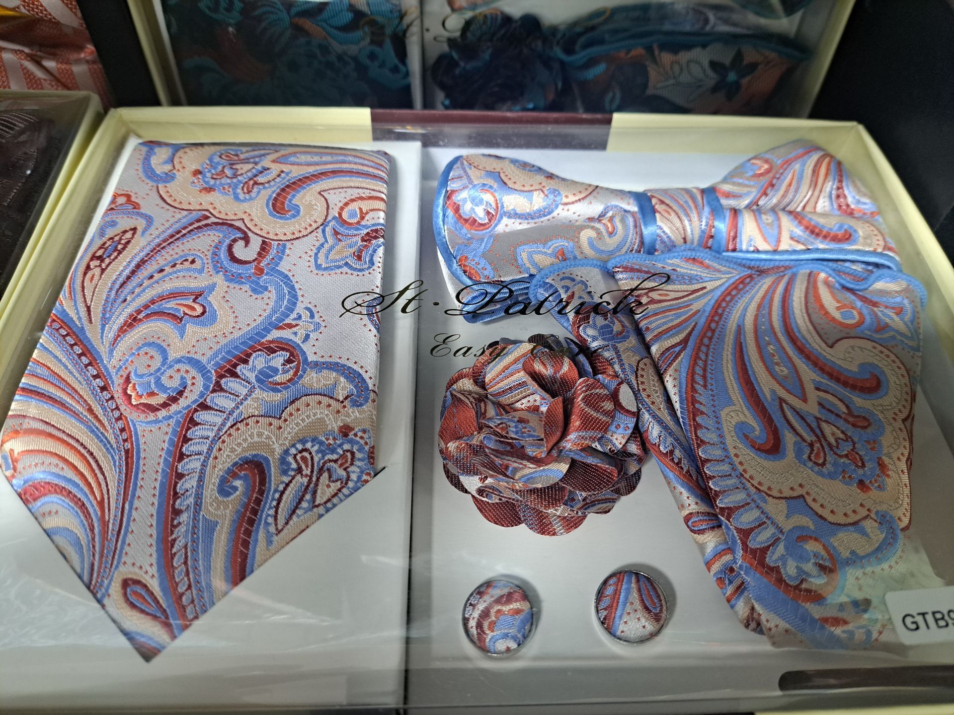 a box with a pastel paisley design tie , bow tie , pocket square and cufflinks