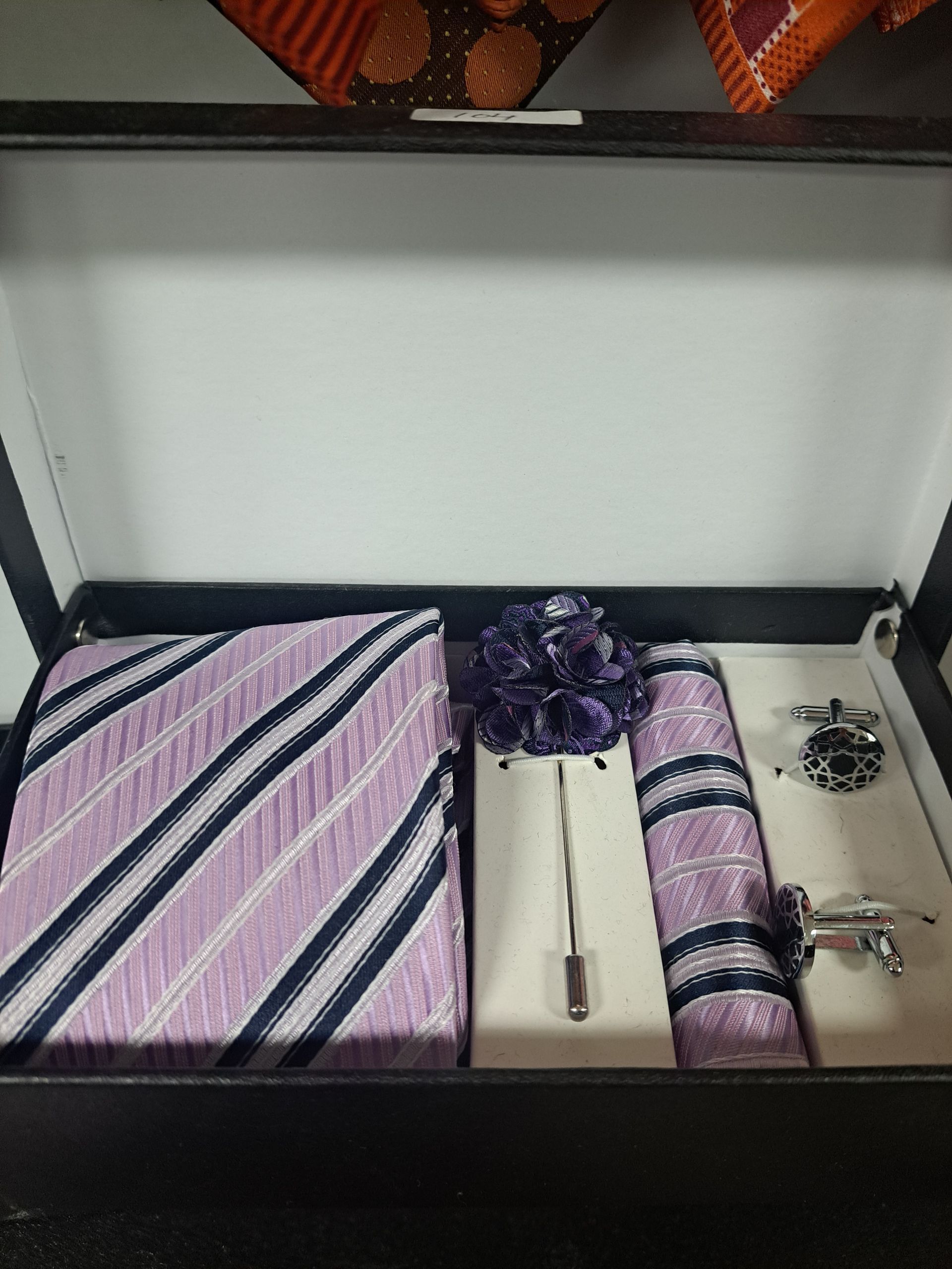 a box with a pink, blue and white striped tie and cufflinks in it,