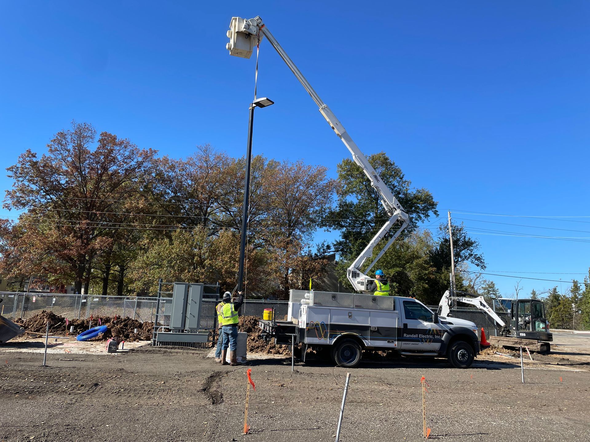 A construction truck with a crane attached to it is working on a street light.