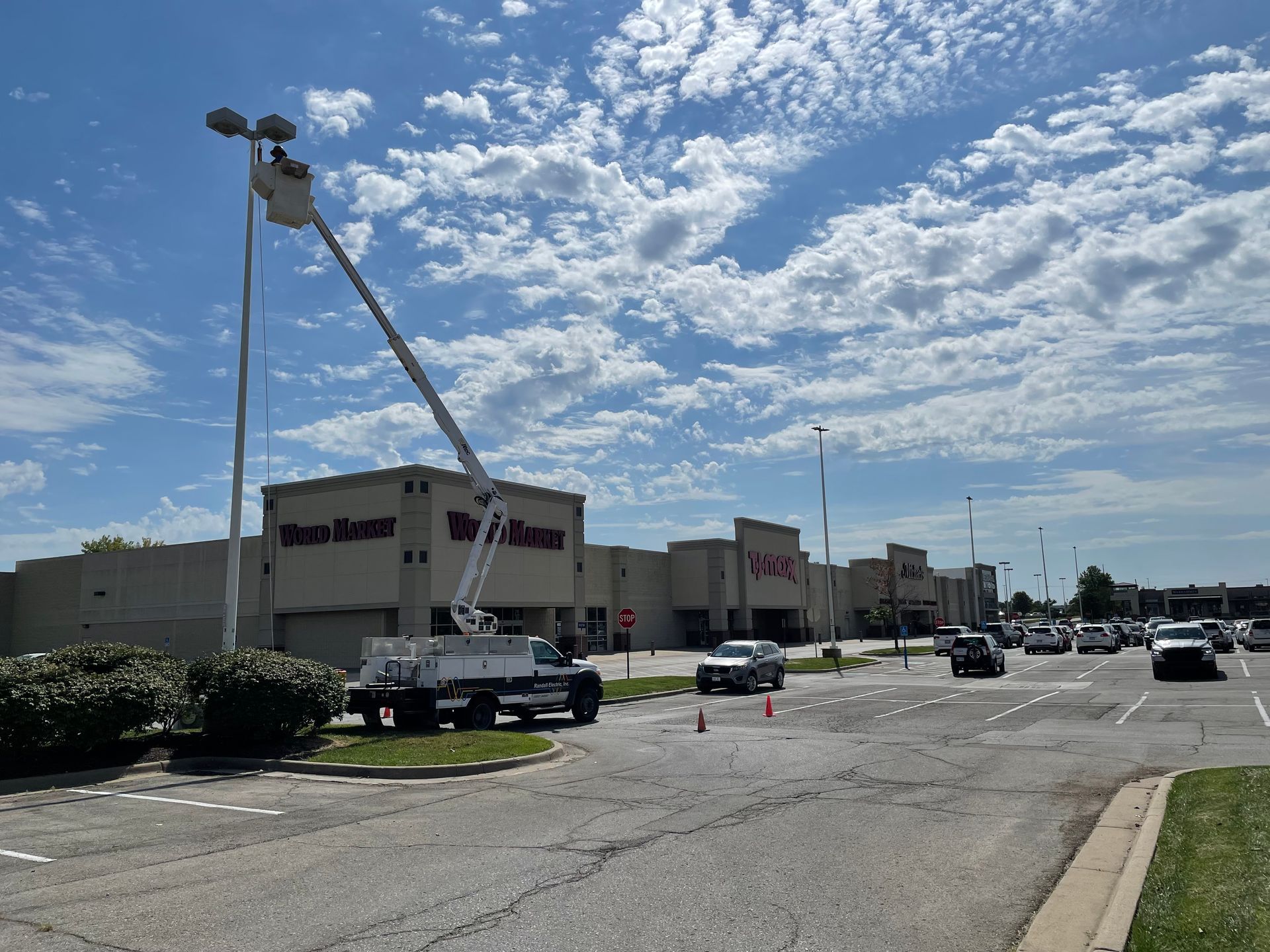 A crane is lifting a street light in front of a store.