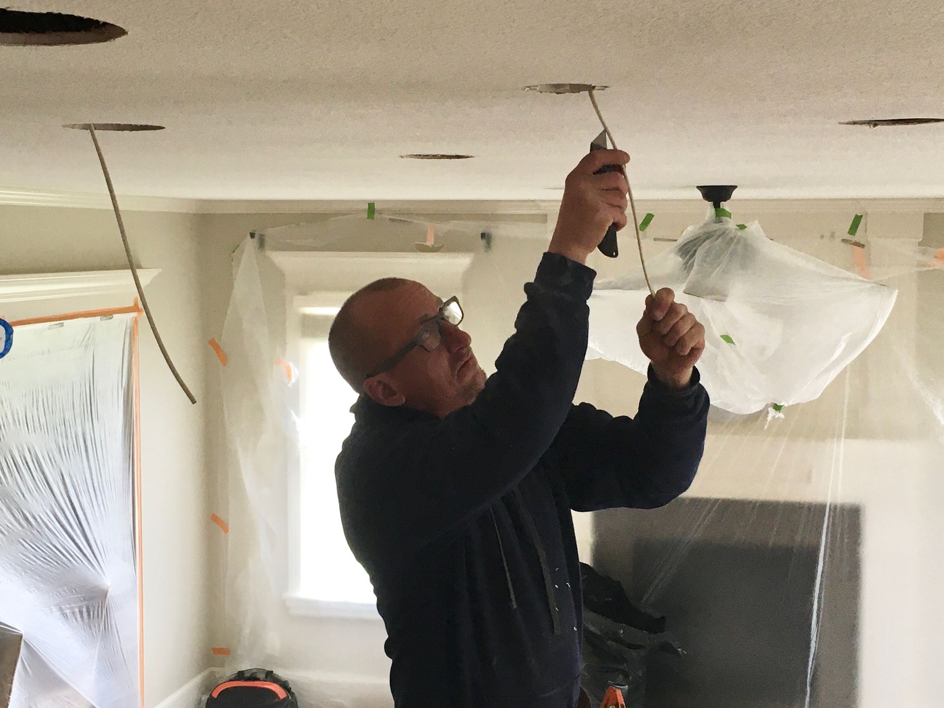 A man is fixing a light fixture on the ceiling.