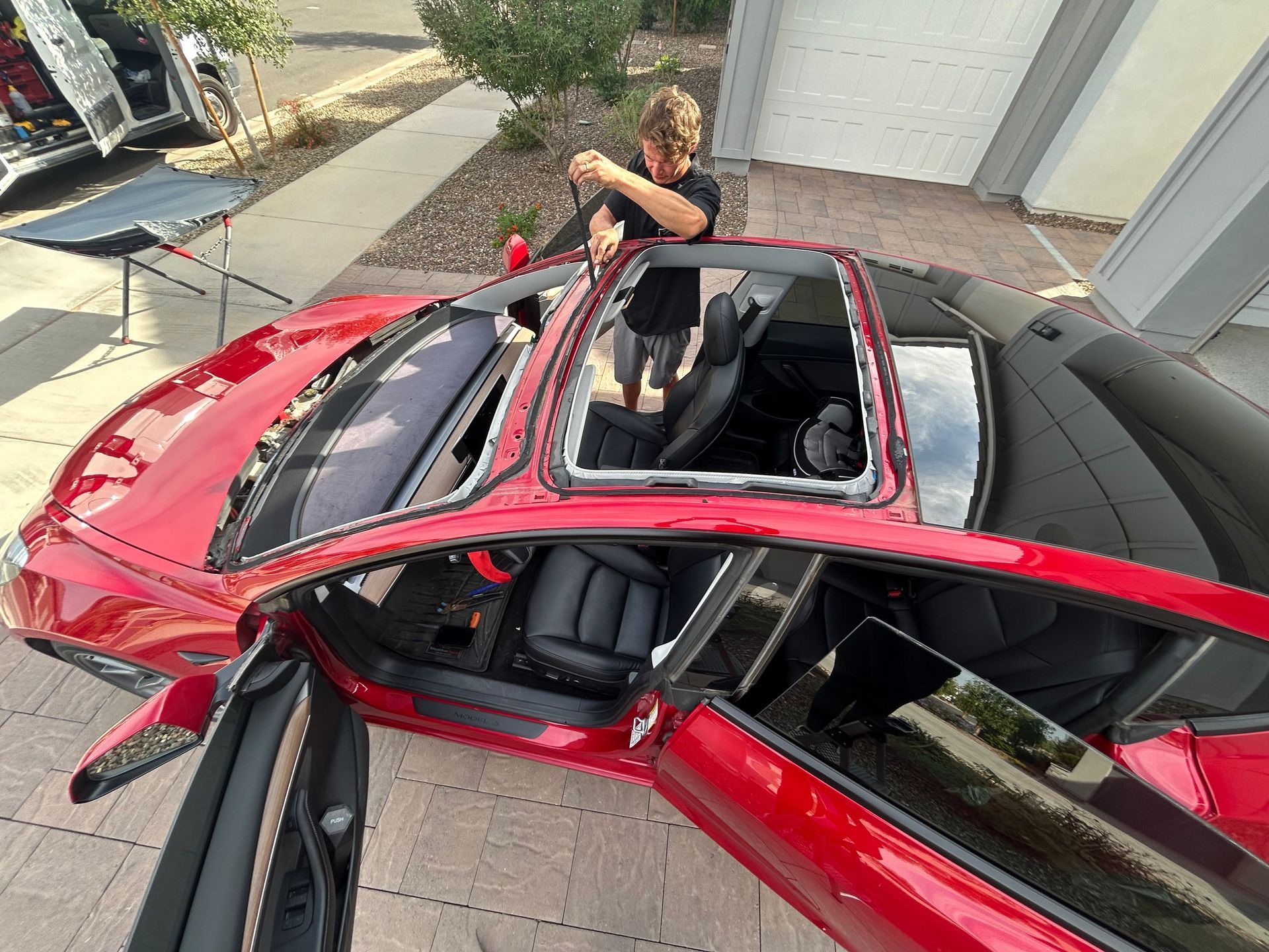 Red sports car with roof open and a person leaning in from outside.