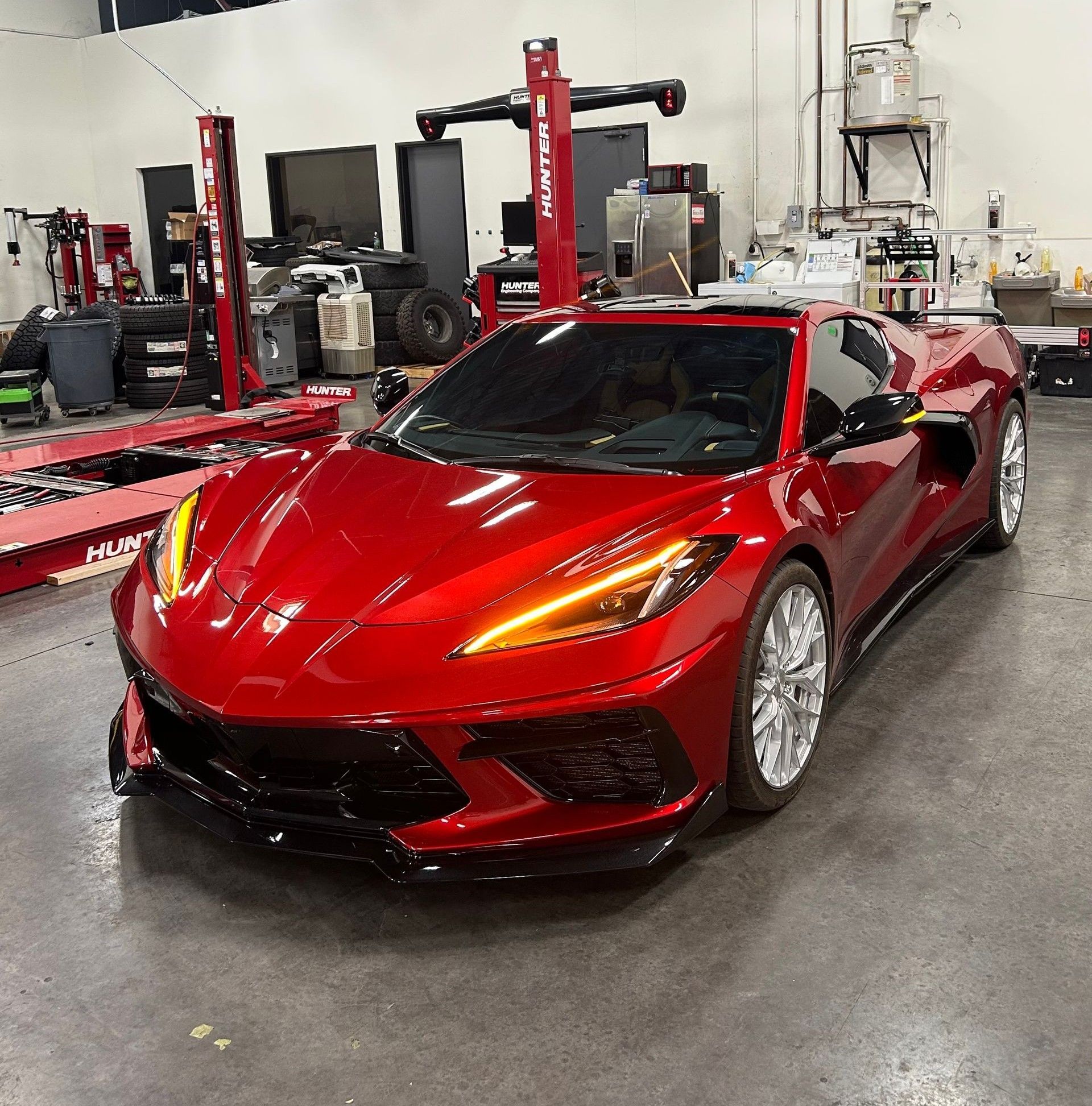 Red sports car in a workshop with lifts and garage equipment in the background