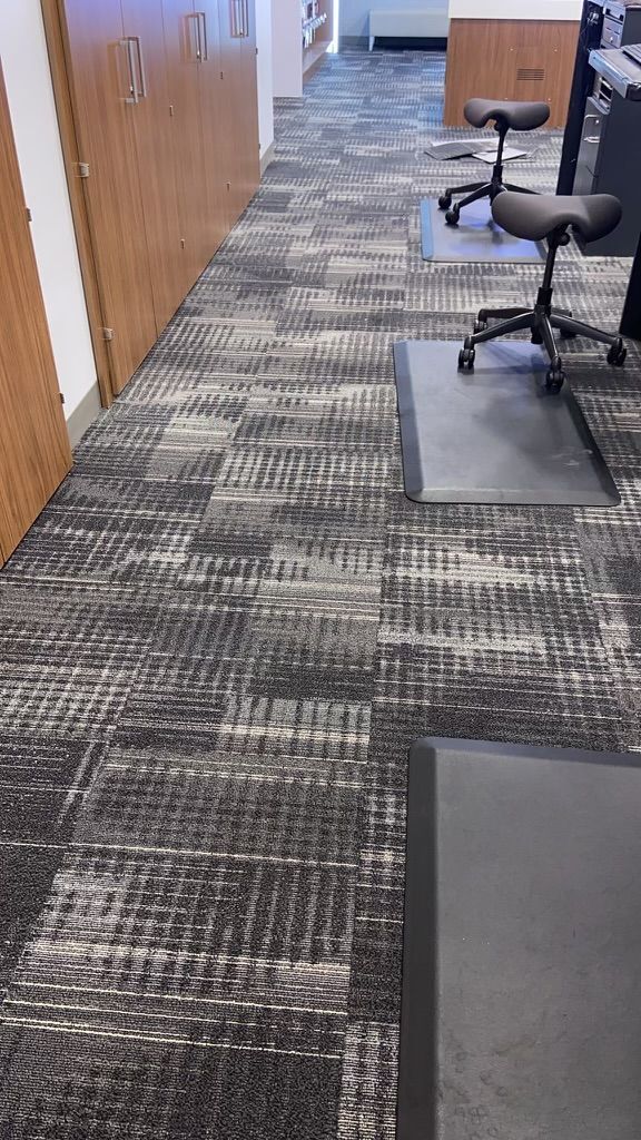 A carpeted floor in an office with a desk and chairs.