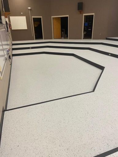 A large room with a white floor and black lines on it.