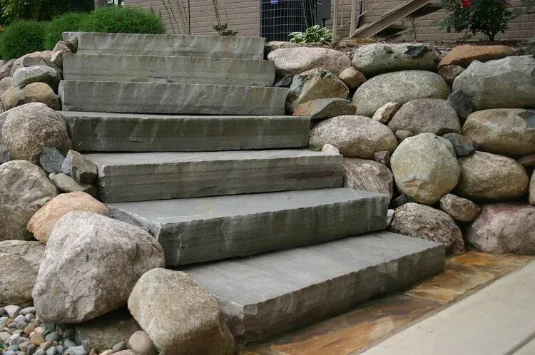 Stone steps leading up a rock retaining wall.