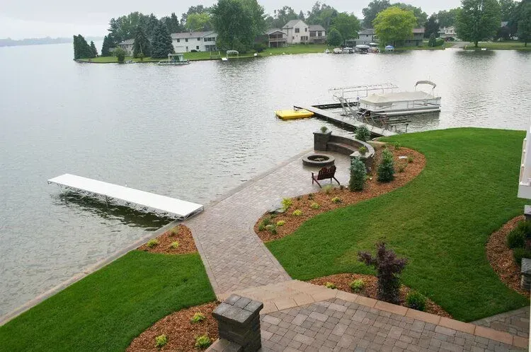 Lakefront property with docks, lawn, and brick patio.
