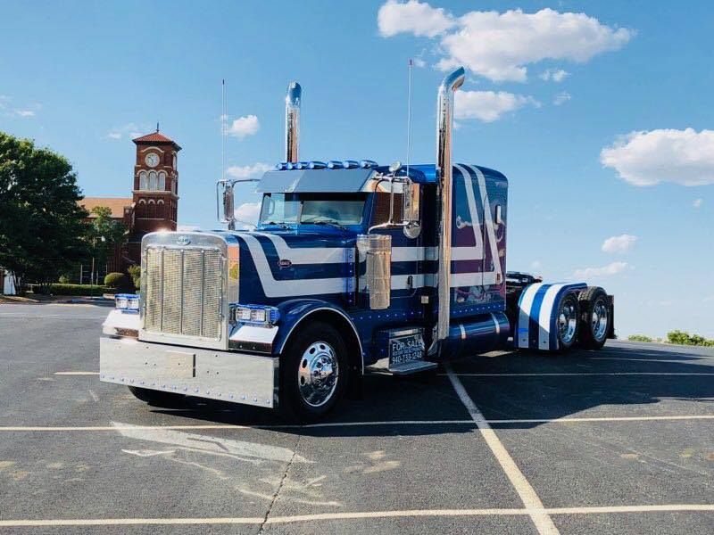 A blue and white semi truck is parked in a parking lot.